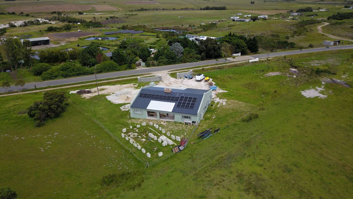From the air: the house on open grass beside the Main Road, with the village and its farmland behind