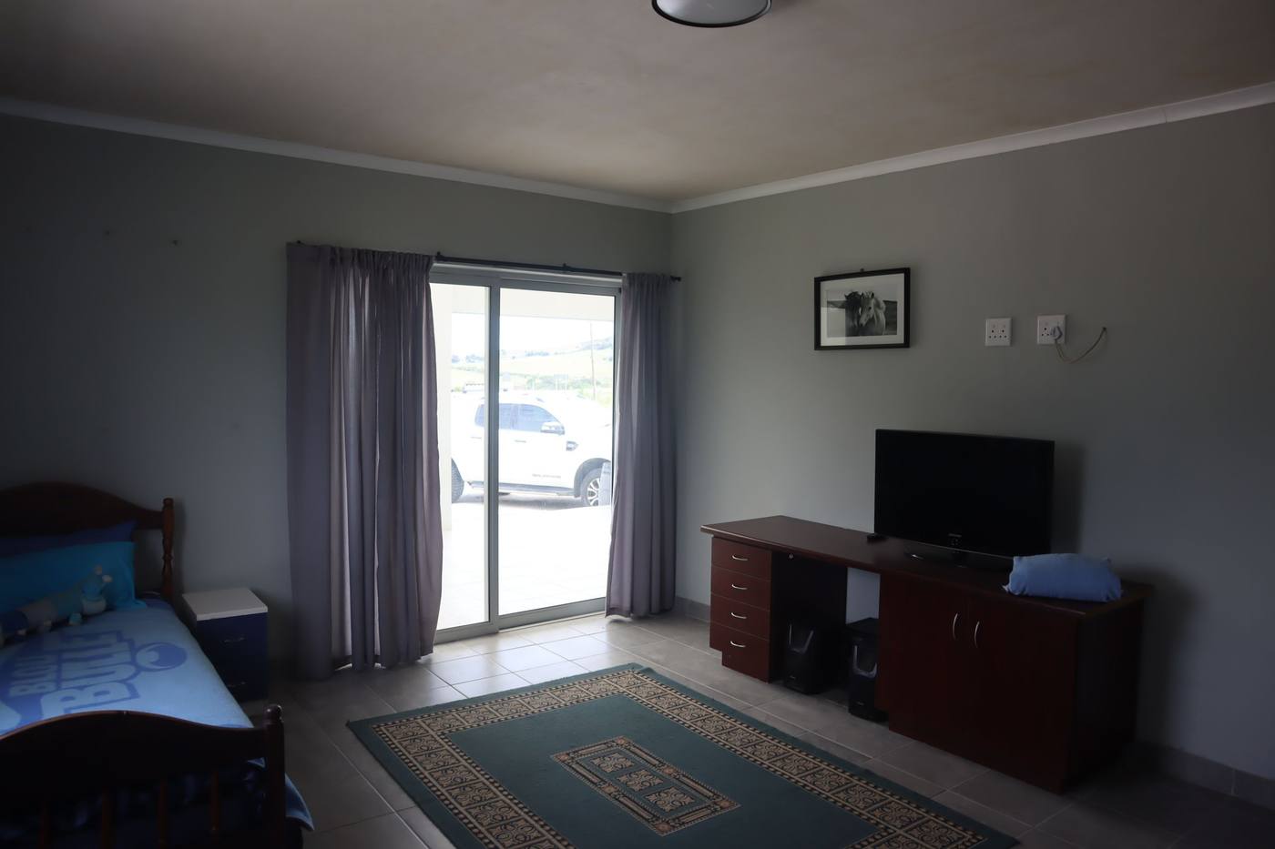 The same bedroom from the other side, with a desk and a television