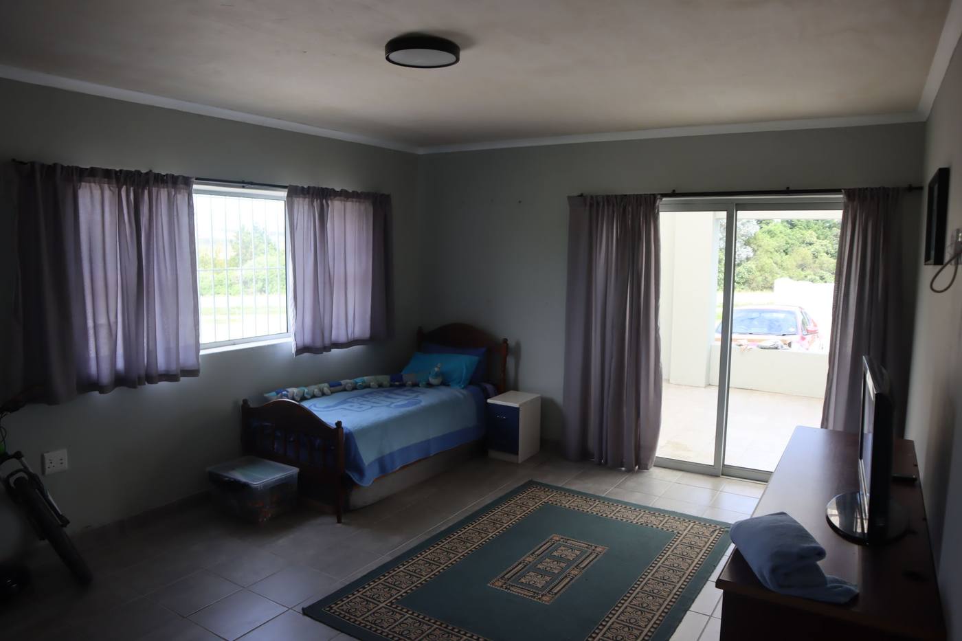 A bedroom with a sliding door out to the stoep