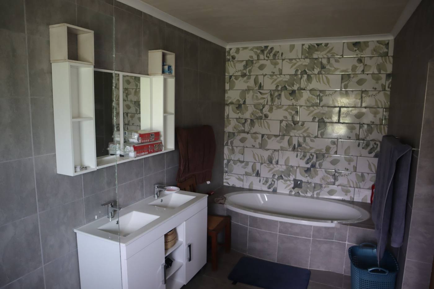 The main en-suite: a bath under a patterned tile wall and a double vanity