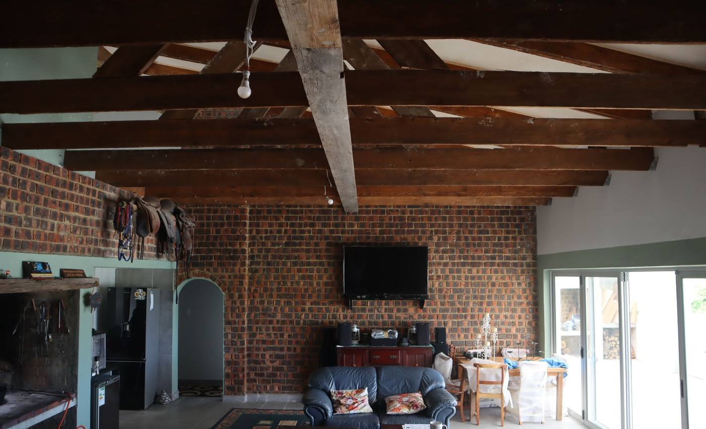 The lounge end of the living area, a television on the brick wall and sliding doors out to the stoep