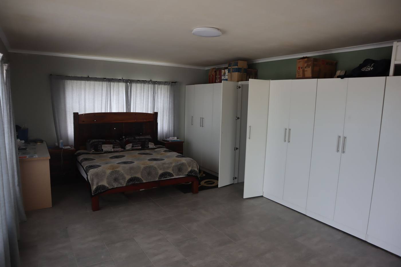 A bedroom with a wall of white built-in cupboards