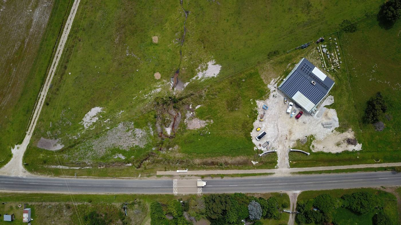 Straight down from above: the roof, the yard and the open land between the house and the road