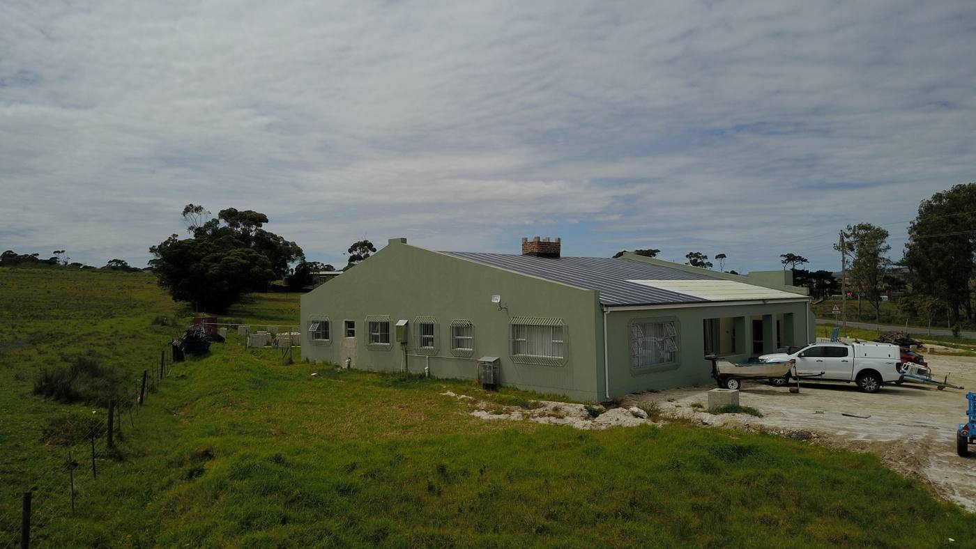 The house from the side: sage-green walls, burglar bars on every window and a gravel yard at the front