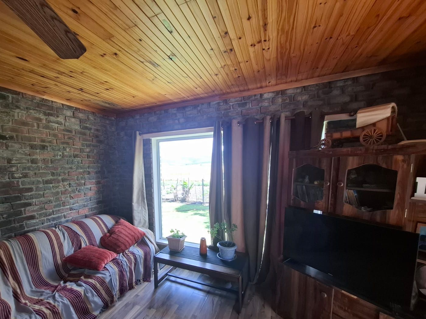 Ein Wohnzimmer mit Sichtziegelwänden, Holzdecke und Holzboden