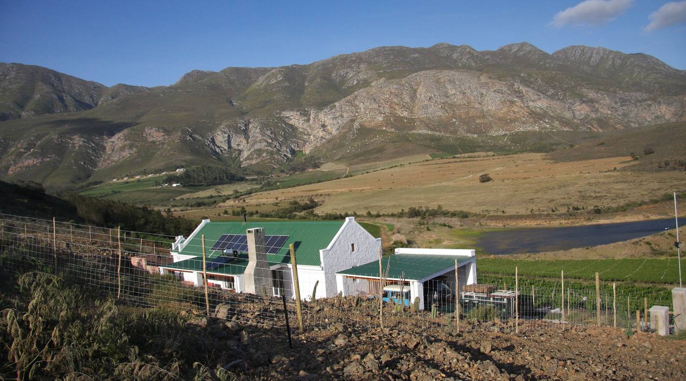 Farm buildings below the bare slopes of the Langeberg, with a dam in the valley
