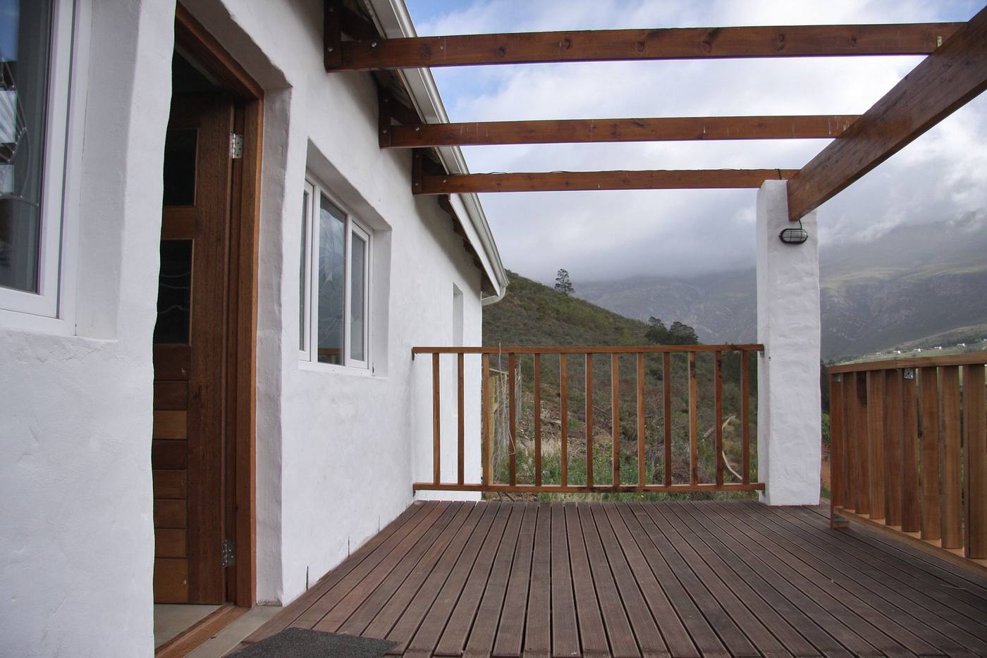 The cottage's timber deck under a pergola, looking out to the mountains