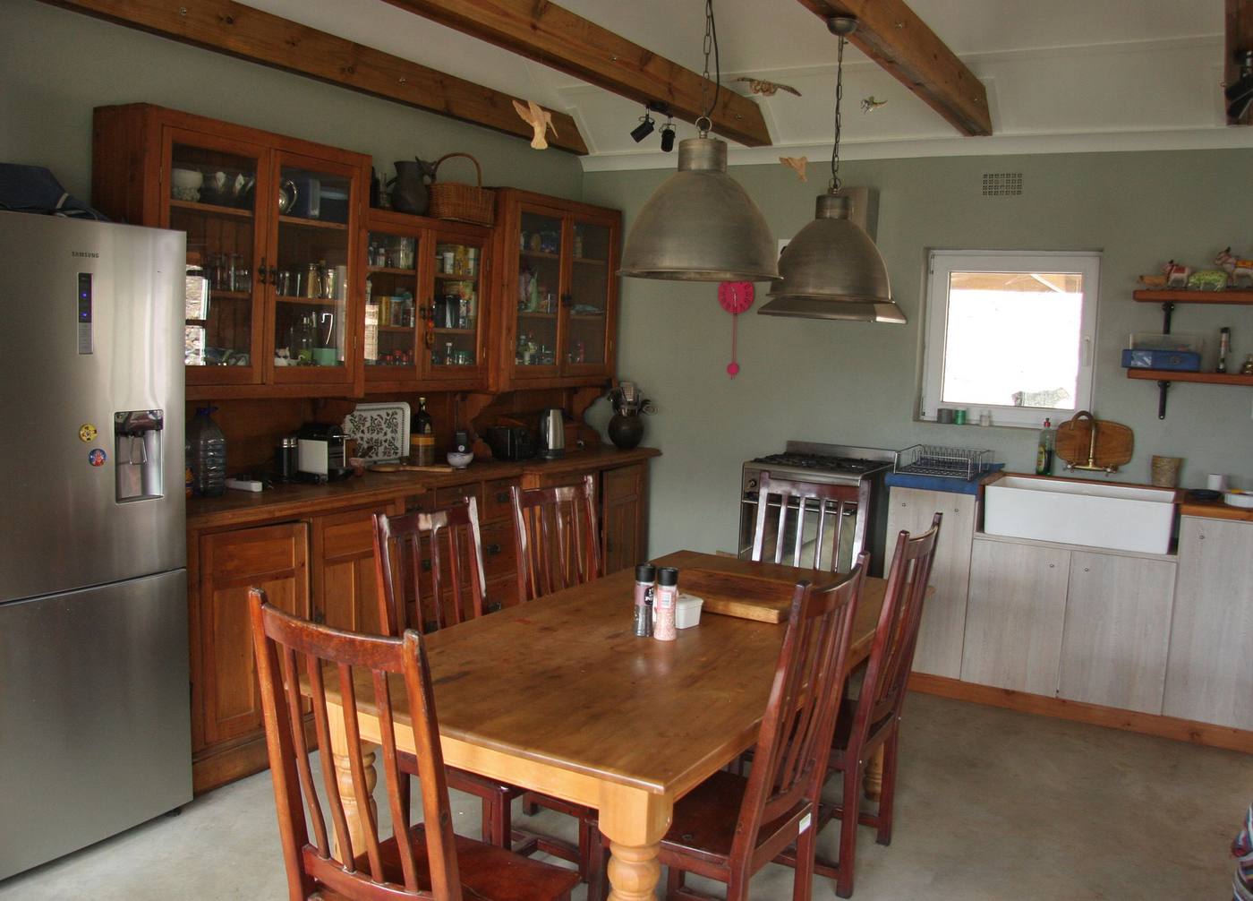 A farm kitchen with glass-fronted timber cupboards, a butler's sink and a long dining table