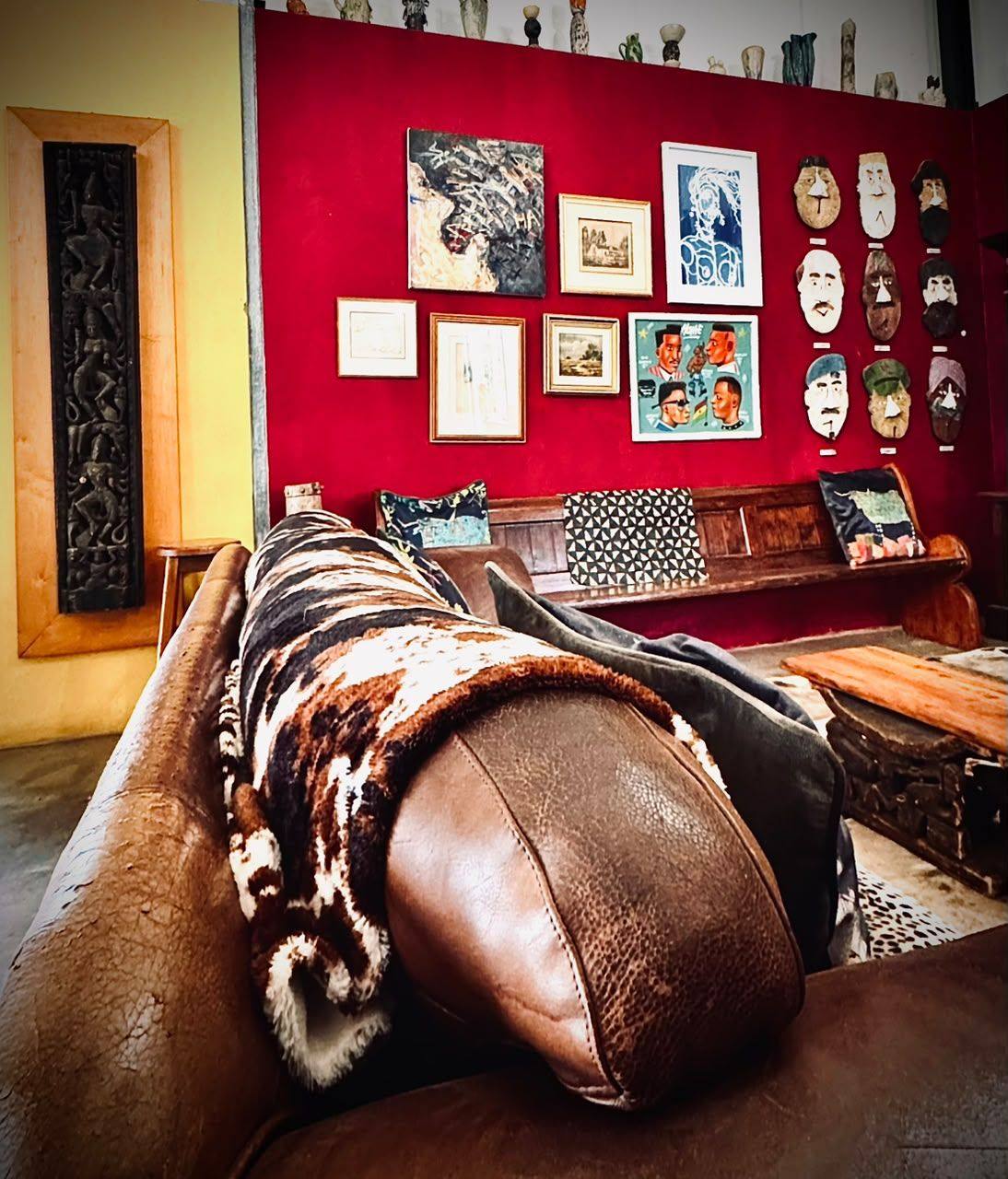 The same red room, a leather sofa in front of a wall of framed pictures
