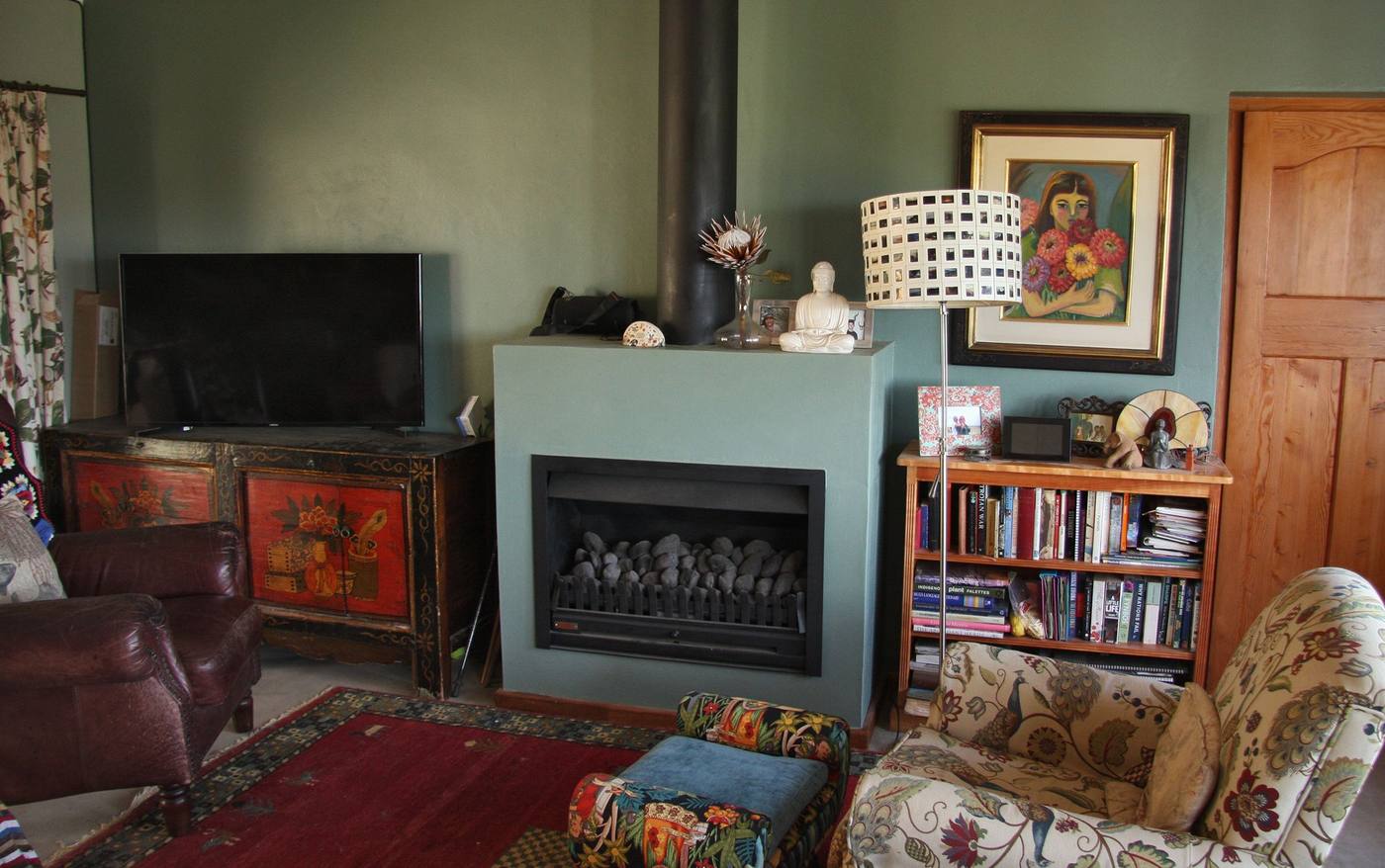 A sitting room with a fireplace, bookshelves and deep armchairs