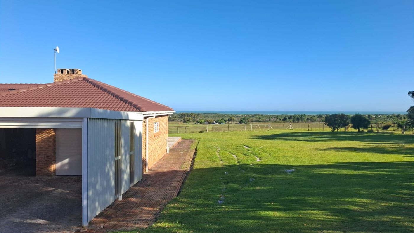 Das Haupthaus mit seiner Garage, hinter dem Rasen das Meer am Horizont