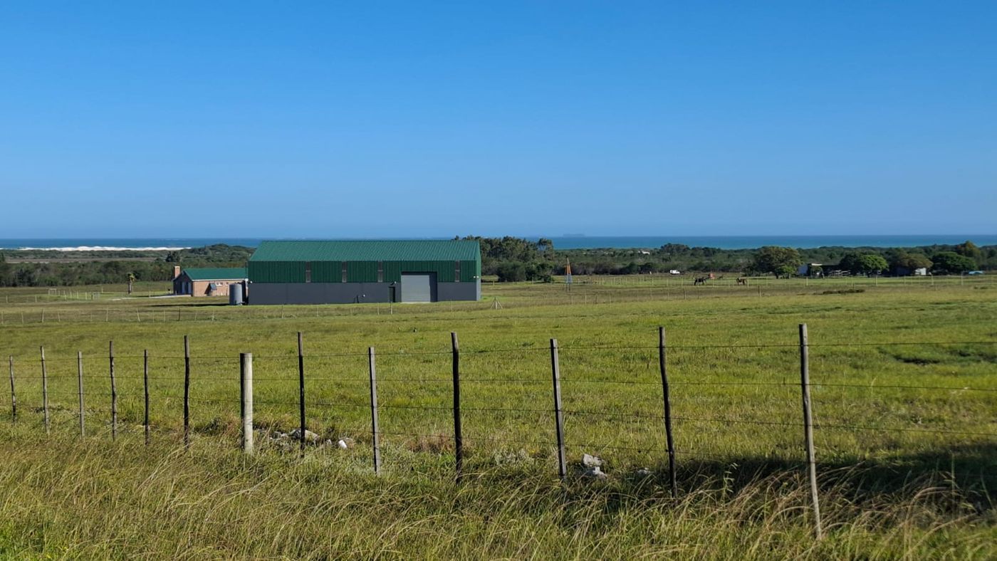 Die Halle jenseits des eingezäunten Weidelands, am Horizont das Meer