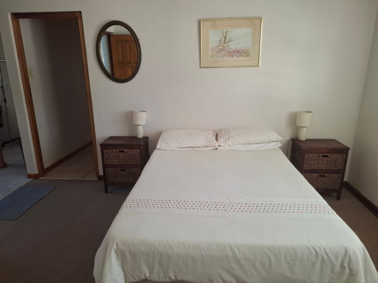 A double bed between two bedside tables in a bedroom with a carpeted floor