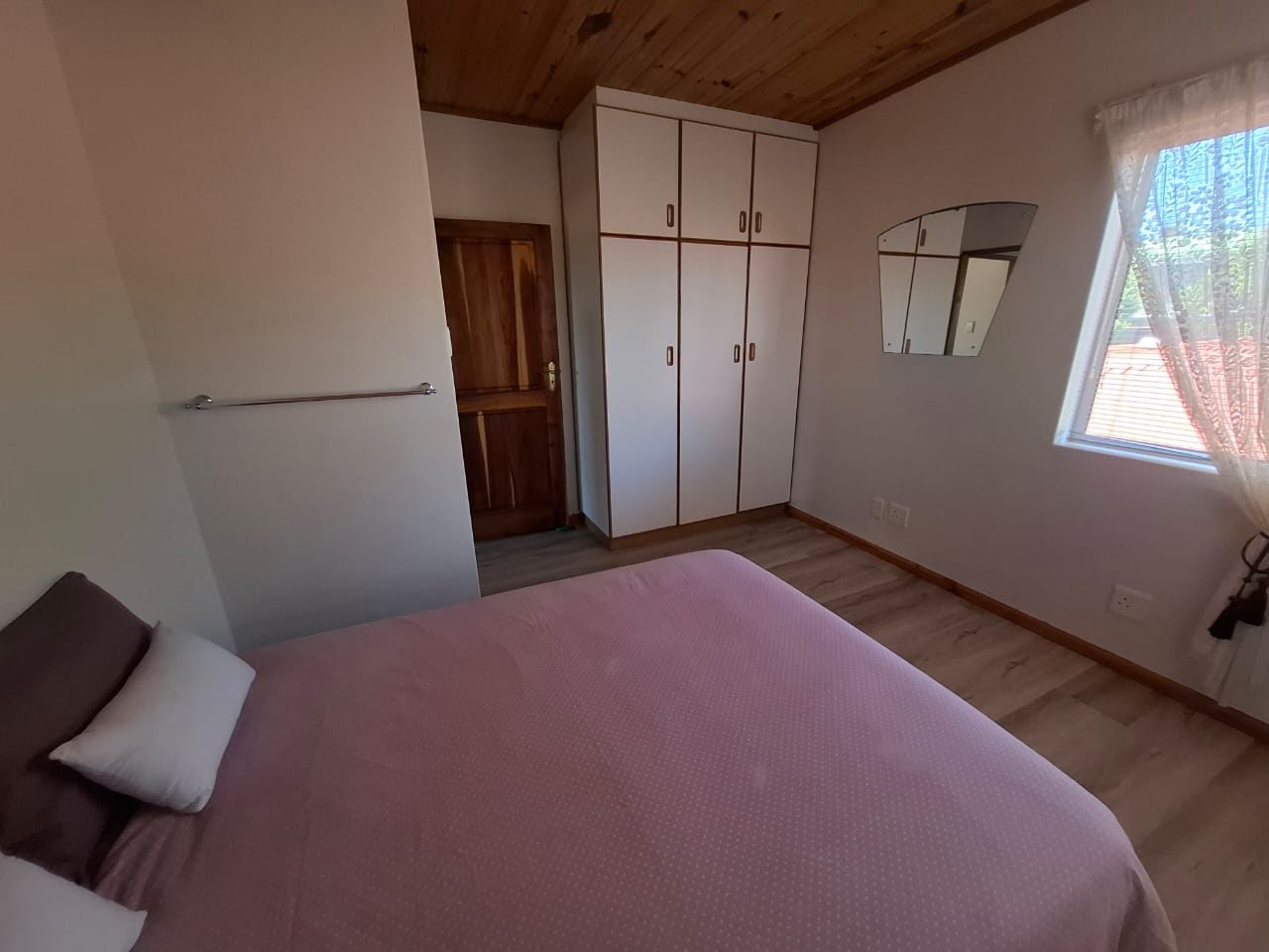 A bedroom with built-in cupboards, a double bed and a window