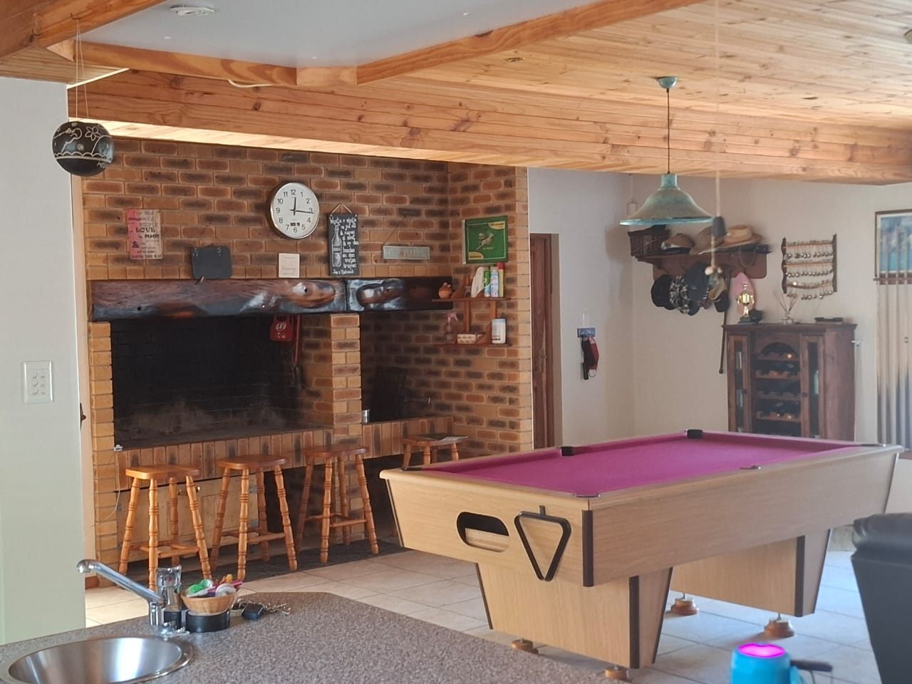 The indoor braai in its brick wall with bar stools in front, and a pool table in the room