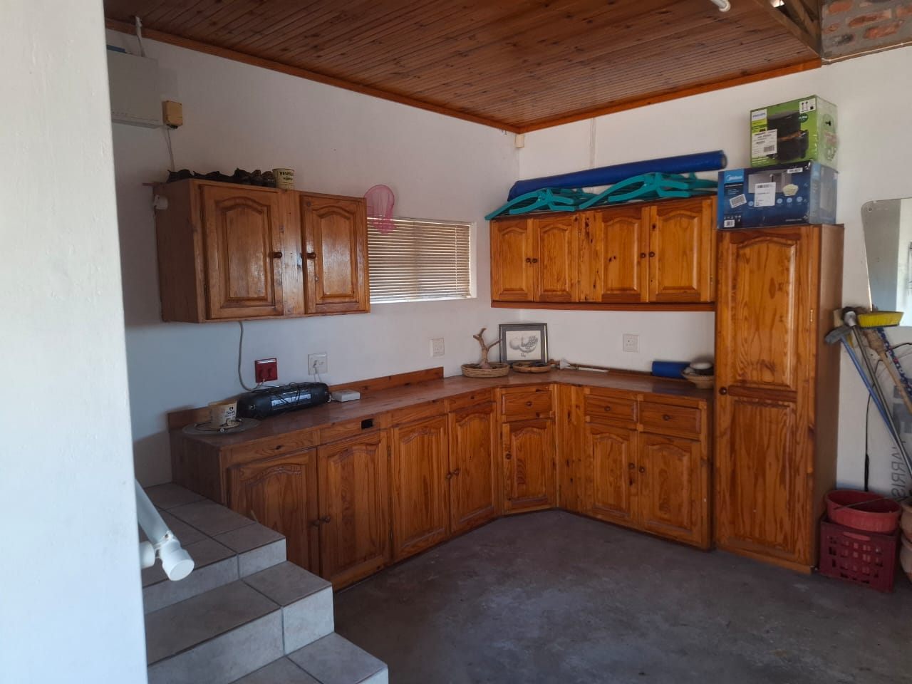 Knotty-pine cupboards and a counter in the garage, with steps up into the house