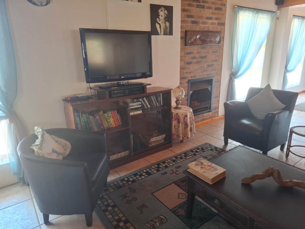 A television on a wooden cabinet beside a fireplace, with leather chairs in front