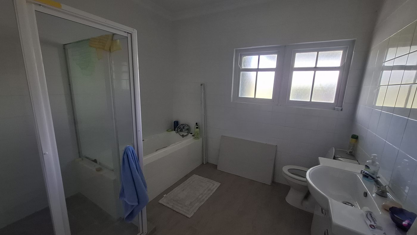 A bathroom with a bath, a shower and two windows