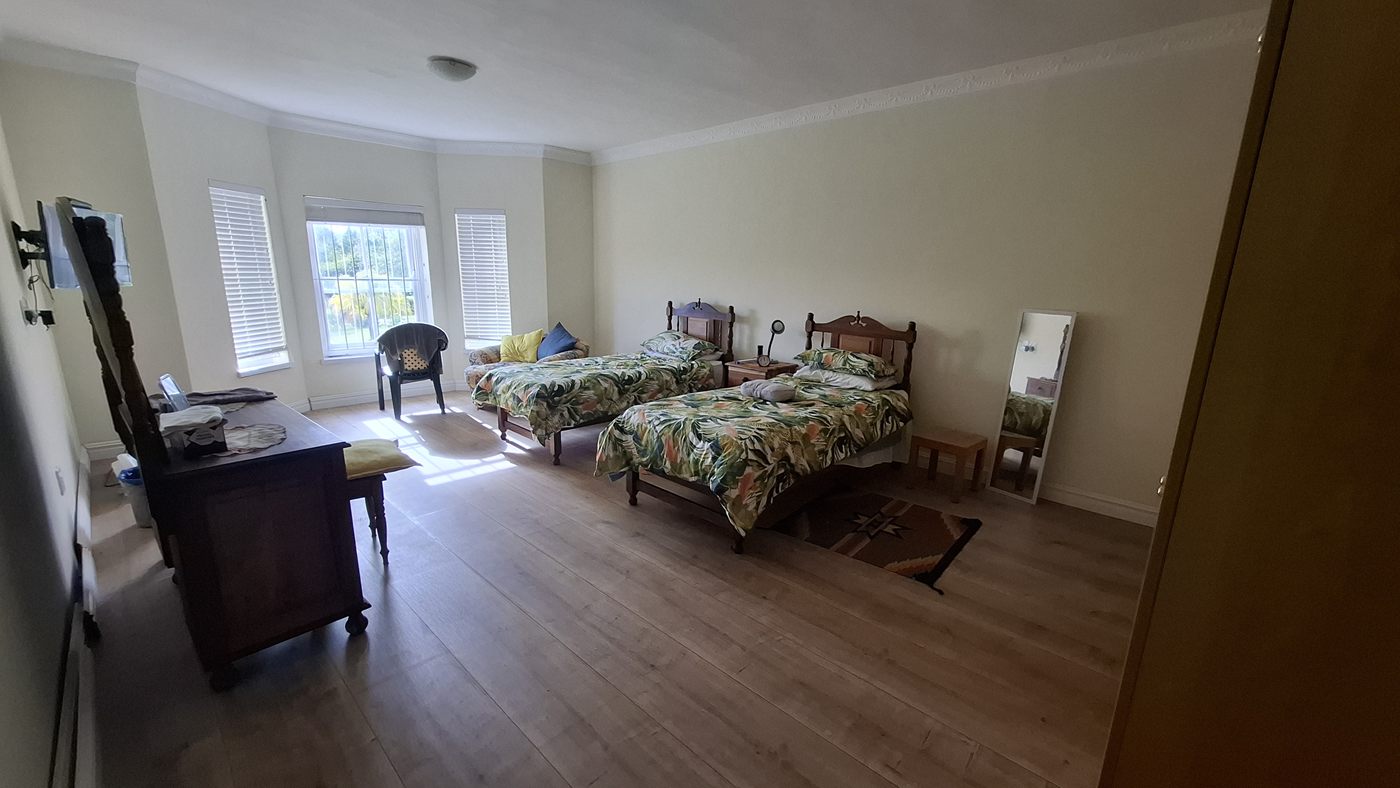 A bedroom with a bay window, a wooden floor and two single beds