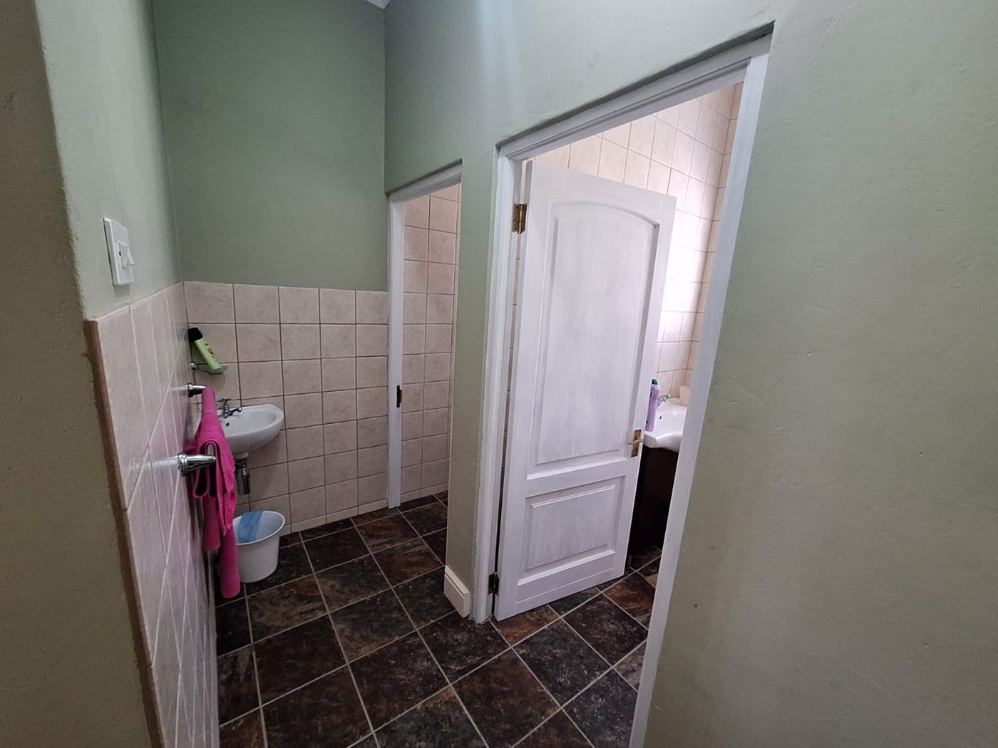 A tiled bathroom off the entertainment room, with a basin and a white door