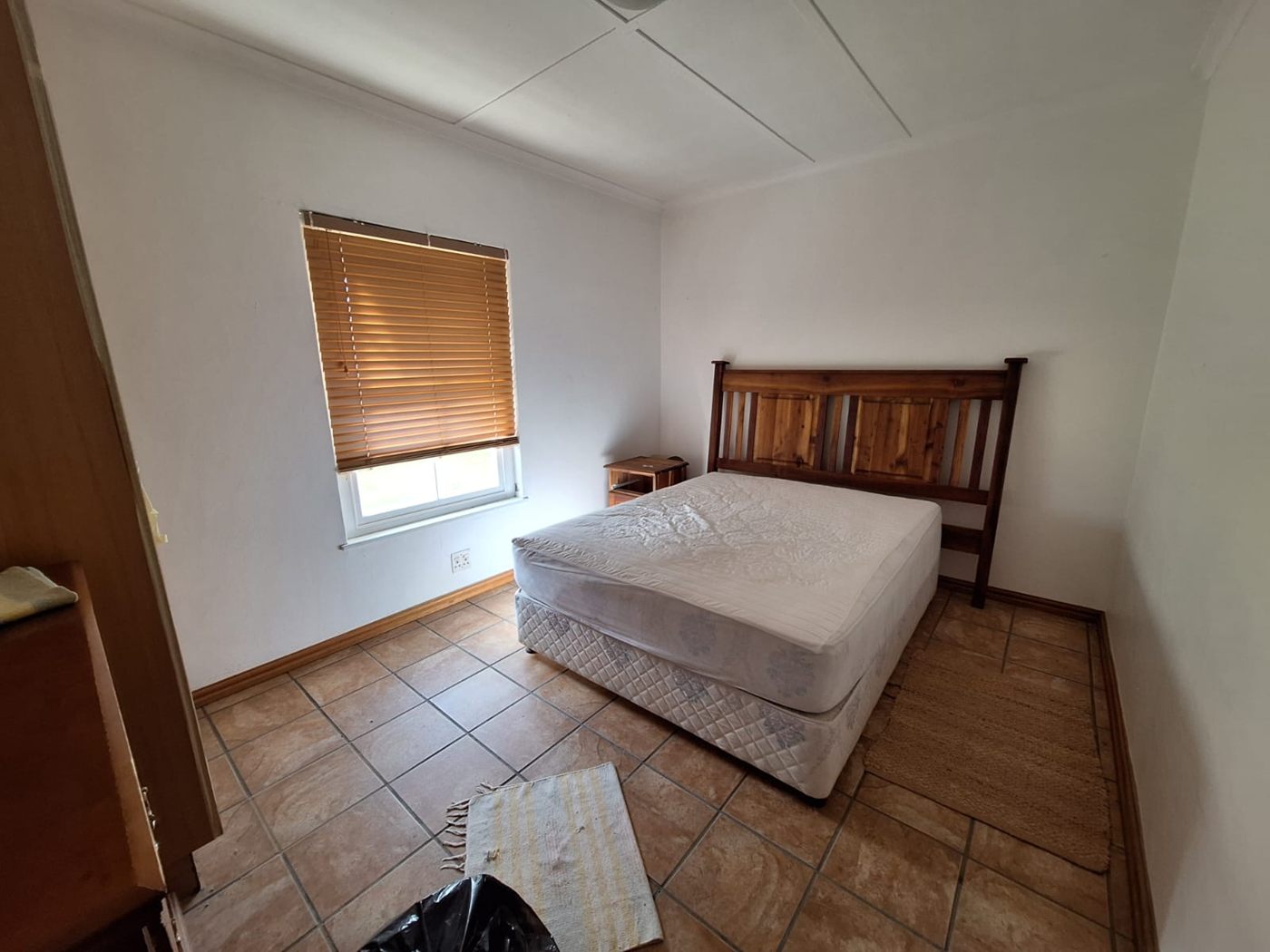 A bedroom with a double bed, a wooden headboard and a tiled floor