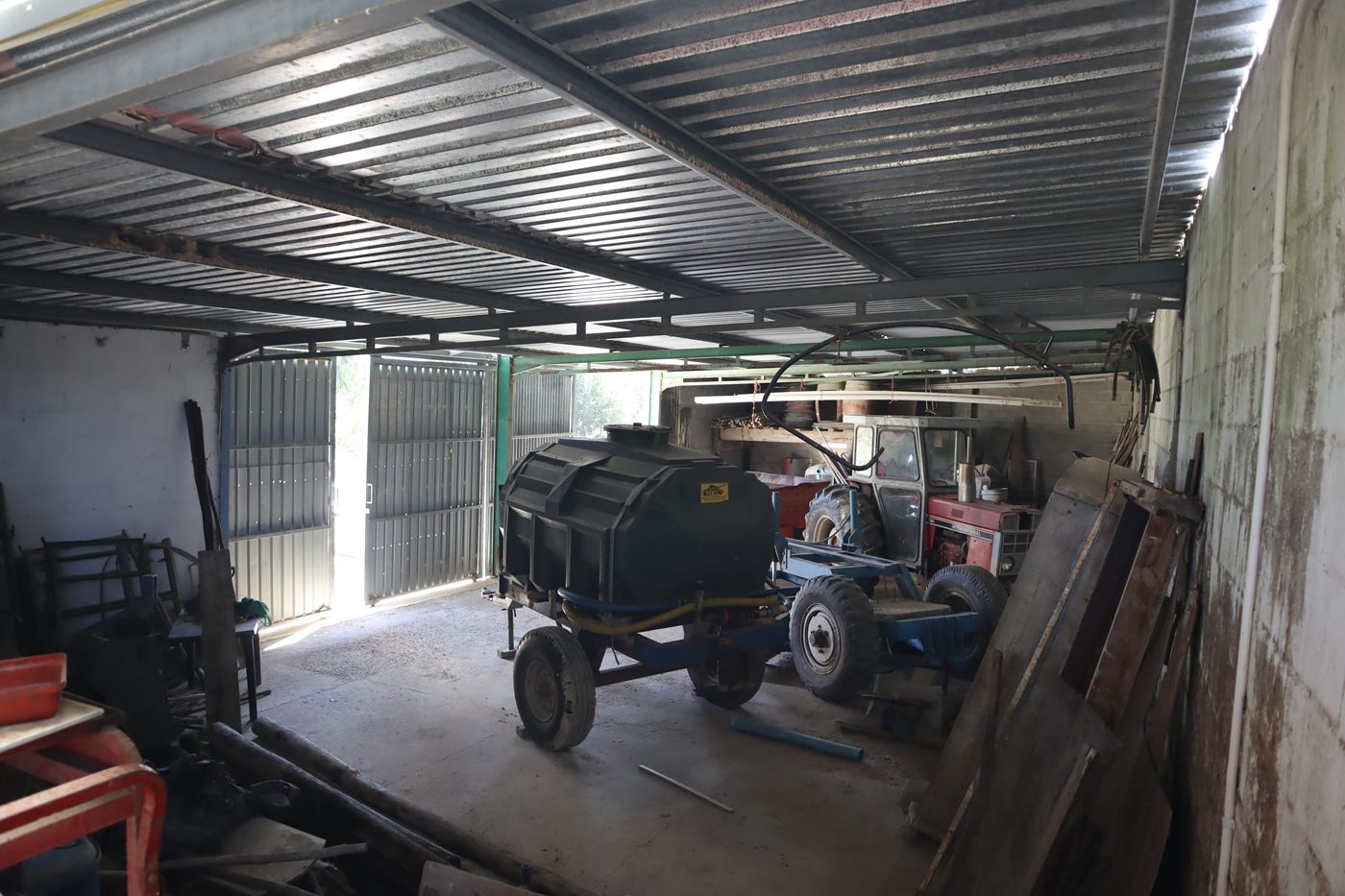 Under a shed roof: a water trailer and a tractor