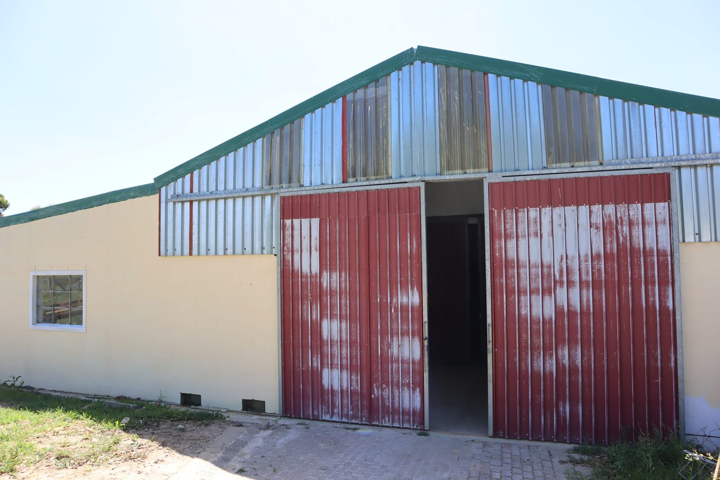 A large shed with red sliding doors under a green-trimmed roof