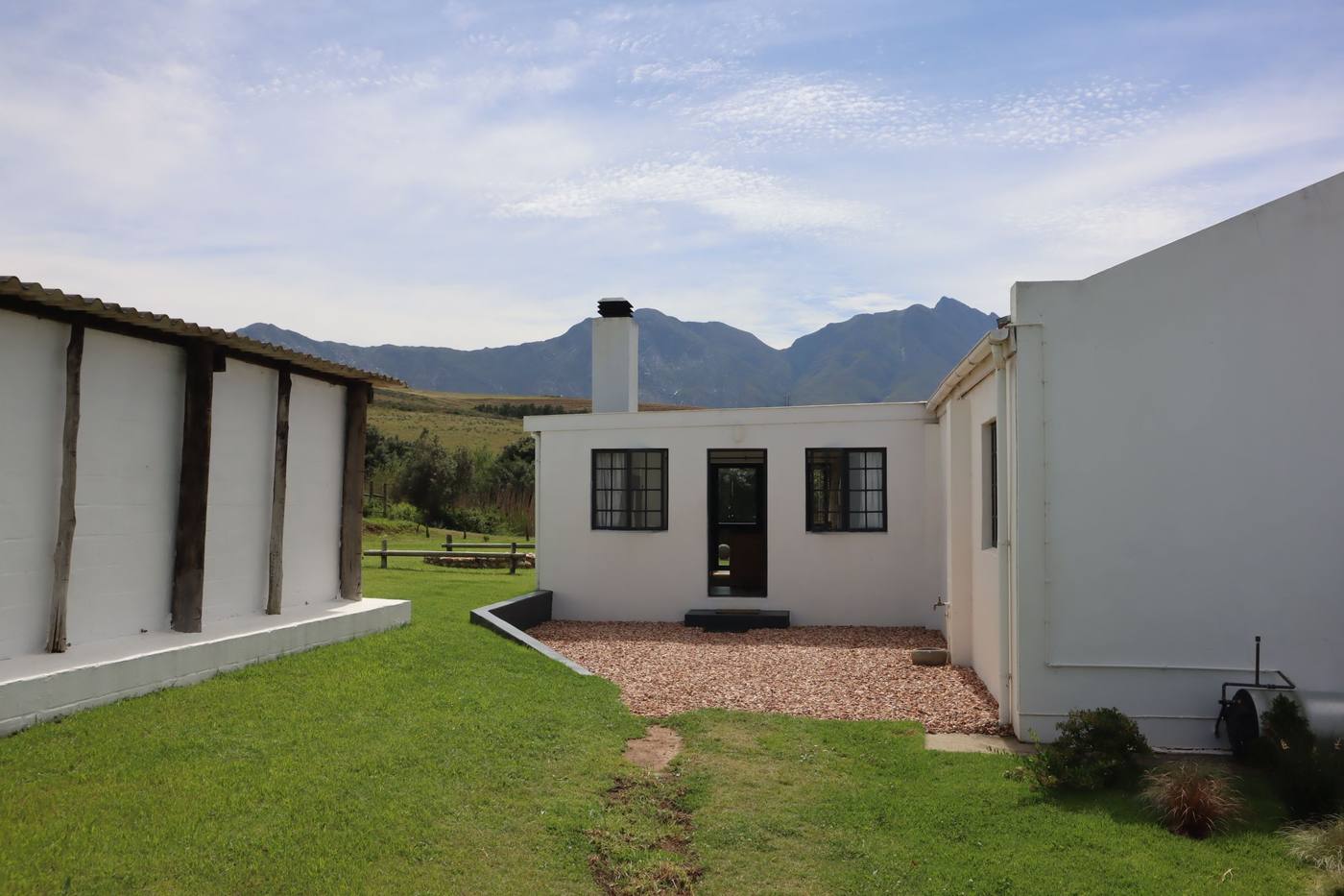 A gravel courtyard between white farm buildings, with the mountains behind