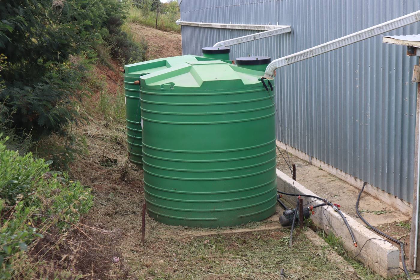 Two green water tanks beside a steel building